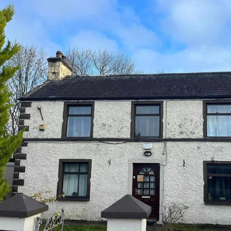 Guttering along the front roofline of a two-storey white-rendered house with a slate roof