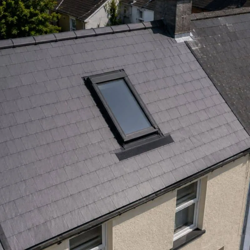 Roof window with dark flashing set into a finished grey slate roof