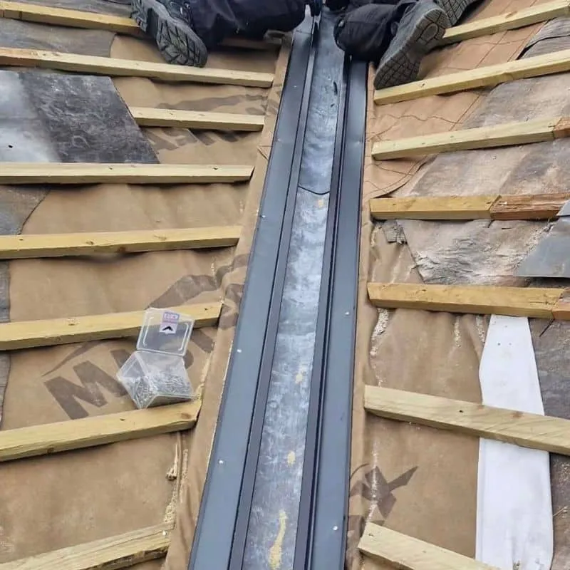 New dark roof valley channel between timber battens and roofing underlay, before the slates are reinstated